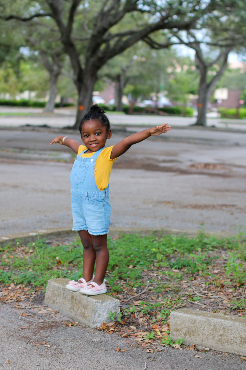 Child with arms extended, standing on stone